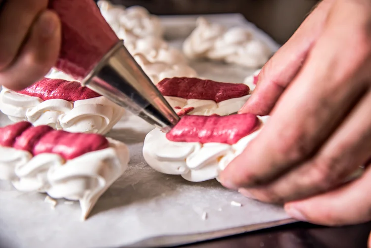 Cukrářský sáček osaďte hladkou trubičkou a naplňte vychlazenou náplní, kterou opatrně vždy dvě bezé k sobě slepte, hladkou stranou k sobě.